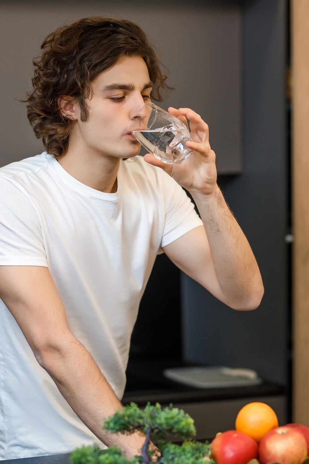 Handsome guy stay on modern kitchen, drinking glass of water in the morning time.