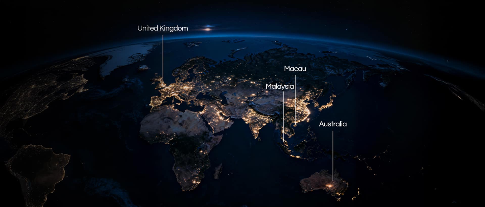 Satellite view of Earth at night showing city lights with labeled locations: United Kingdom, Macau, Malaysia, and Australia.