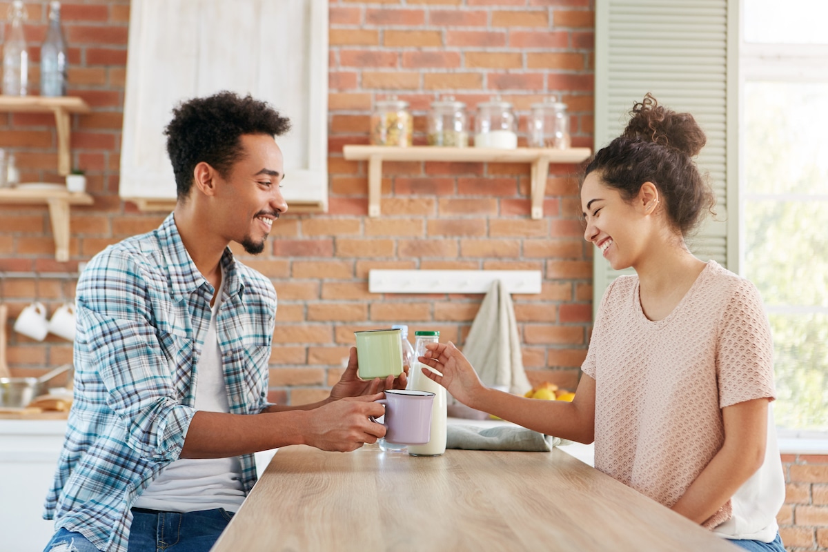 Young man and woman sharing a cup of coffee in the kitchen.